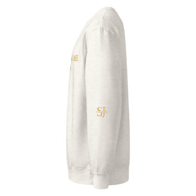 Vue de profil du sweat-shirt premium SJ EXCLUSIVE écru, logo SJ doré sur la manche, coupe droite en coton doux – style chic et décontracté.