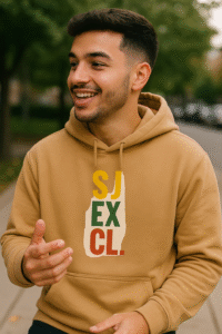 Homme souriant portant un hoodie camel SJ EXCLUSIF – logo SJ EXCL multicolore style streetwear premium